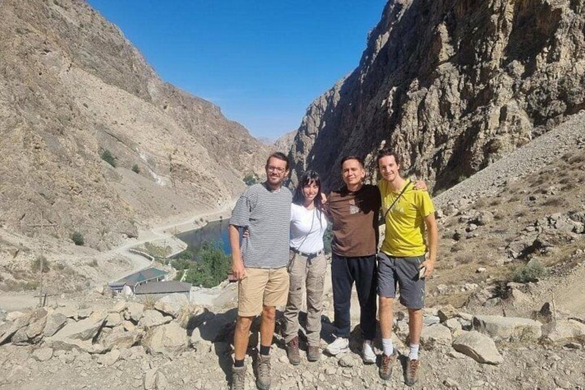 Cuatro personas en terreno rocoso, con montañas al fondo. 2