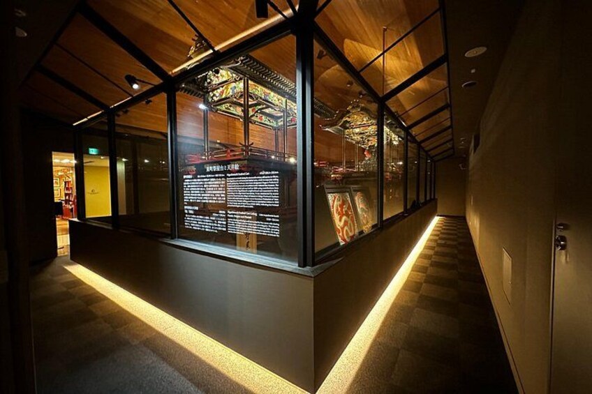 A corridor with glass walls, wooden ceiling, and a lit floor. 4