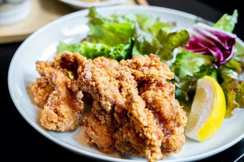 A plate of fried chicken with a side of mixed greens and a lemon wedge. 5