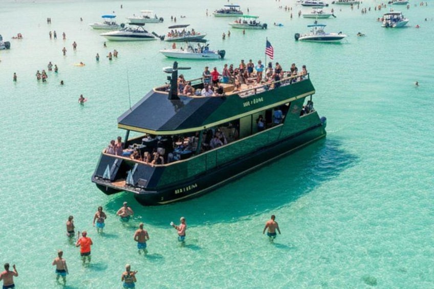 Ein großes Boot mit Passagieren an Bord und weiteren Personen, die im Wasser schwimmen. 4