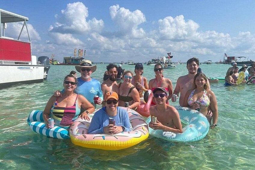 A group of people on inflatable rafts in a body of water with boats in the background. 3
