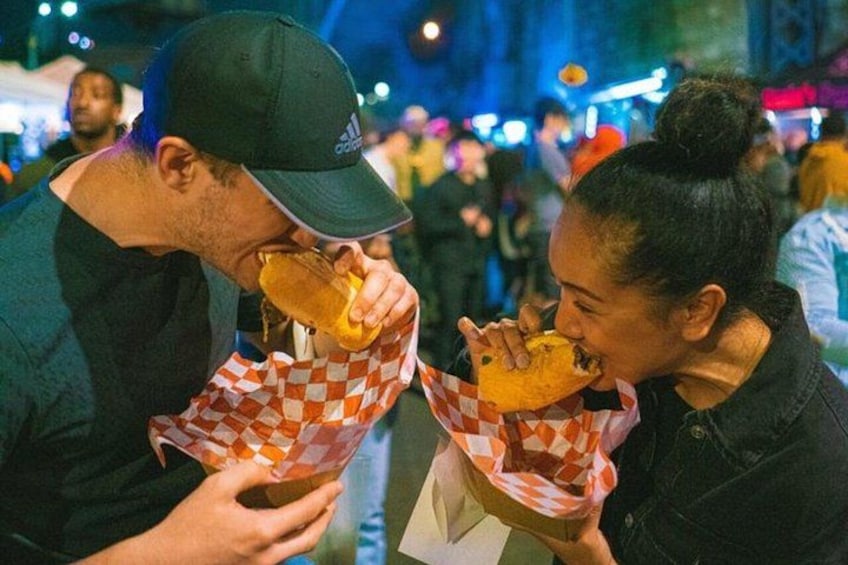 Two people eating burgers at night. 1