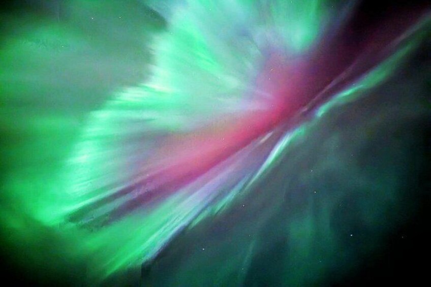 A vibrant aurora borealis display with green and pink hues. 1