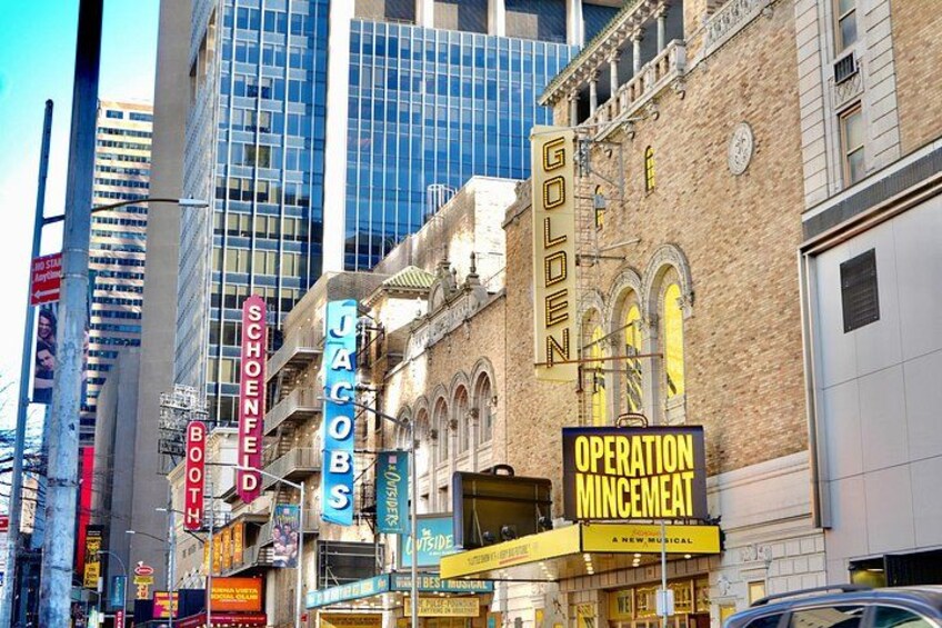 A city street with historic buildings, neon signs, and a modern glass skyscraper. 2