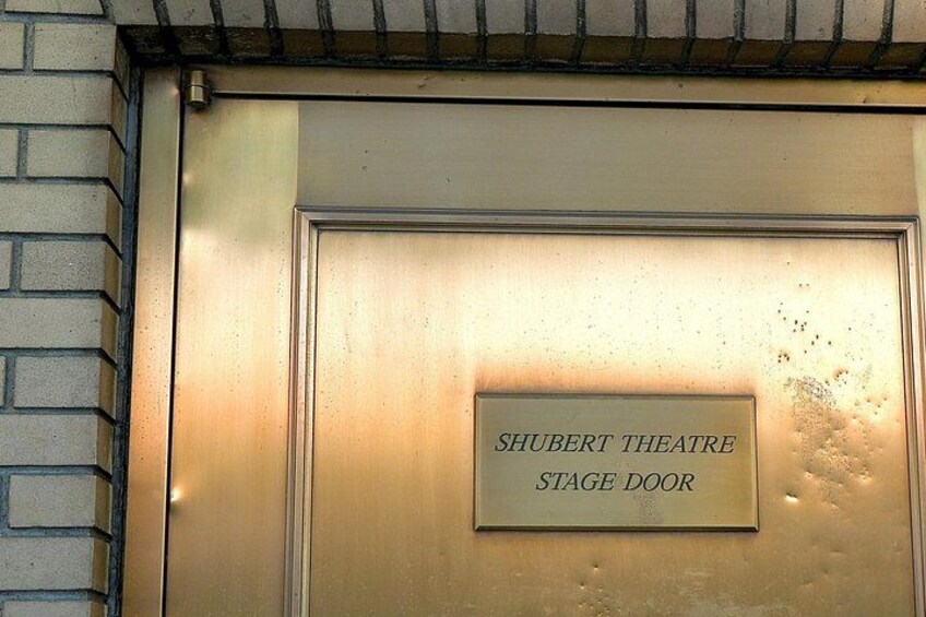 A metallic door with a plaque that reads 'SHUBERT THEATRE STAGE DOOR'. 3