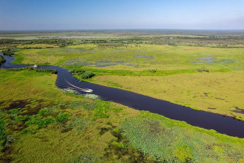 A river winding through a green landscape with a boat on the water. 2
