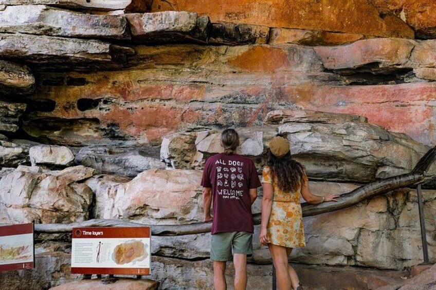 A couple standing in front of a rocky wall with a sign about the geological history. 4