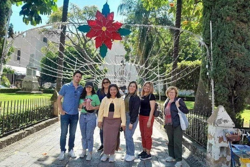 A group of people posing in a park with a large flower decoration and a fence in the background. 5