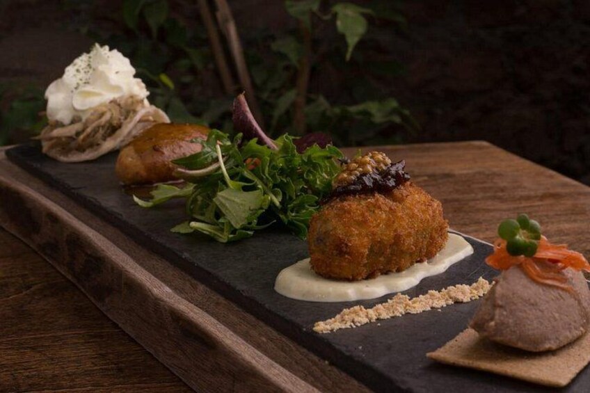 Una mesa de madera con una variedad de platos, incluyendo un elemento empanizado, una ensalada y un postre. 5