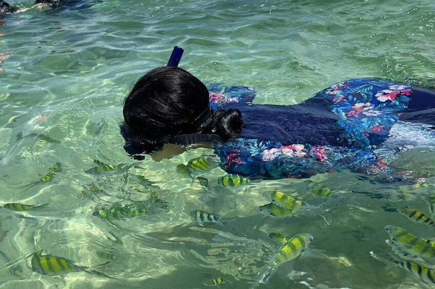 A person snorkeling in clear water with fish. 2