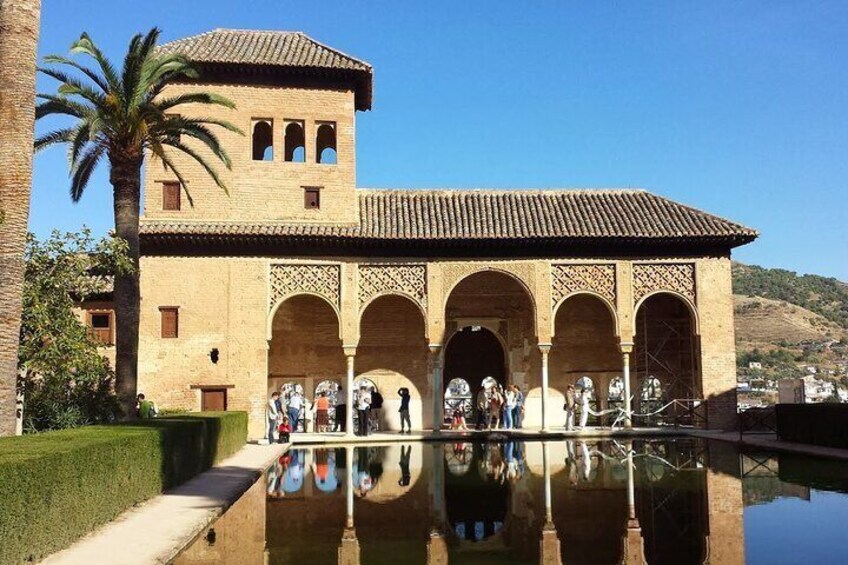 Un edificio histórico con arcos y una piscina que refleja su estructura. 1