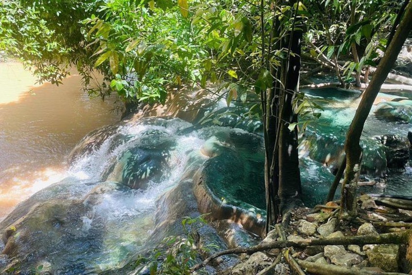 A waterfall cascading over rocks, surrounded by lush greenery and trees. 1