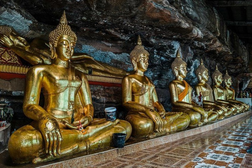 A row of golden Buddha statues in a cave. 4