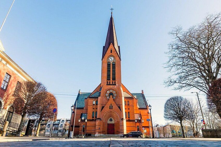 A church with a tall steeple, a clock, and a red brick facade. 3