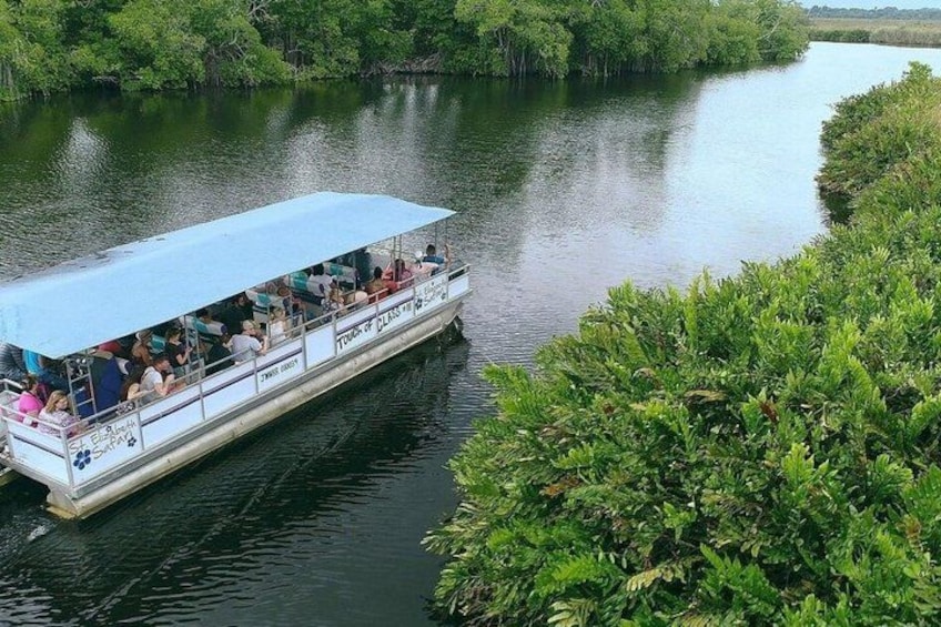 A boat with passengers, surrounded by lush greenery and calm water. 4