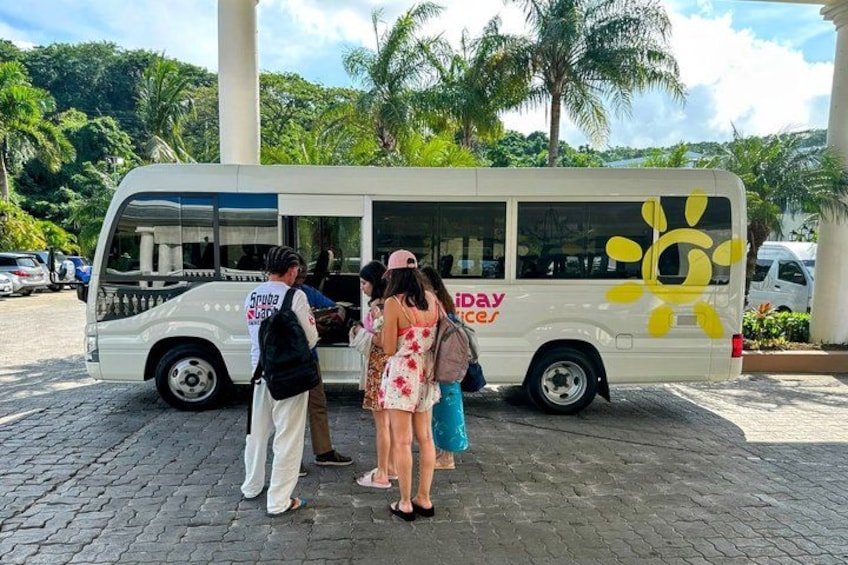 A white bus with a yellow sun design and the words 'Spuday Services' parked on a cobblestone surface. 3