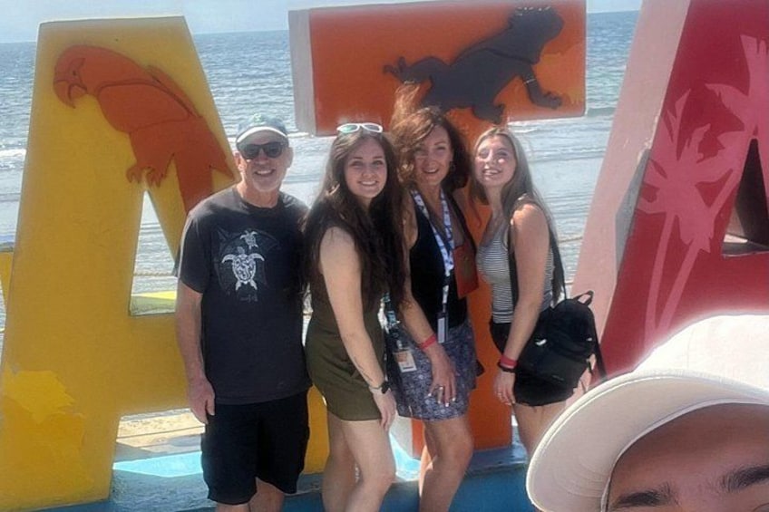 People standing in front of large letters and a boat. 3