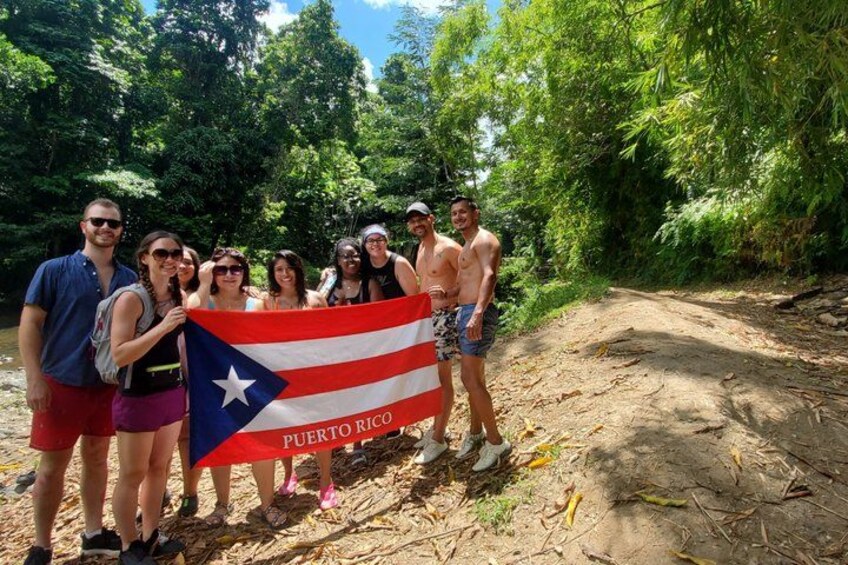 A group of people holding a Puerto Rico flag in a forested area. 3