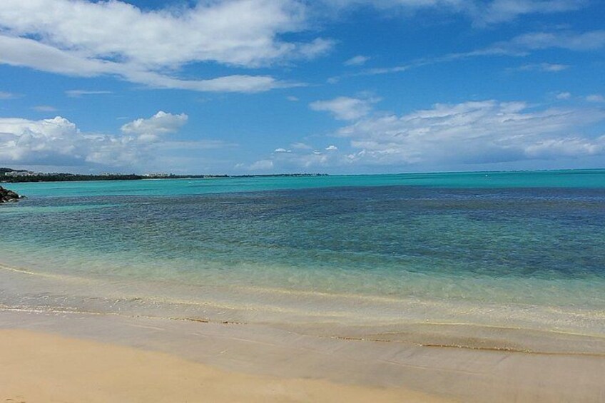 A beach with clear turquoise water and a sandy shore. 3