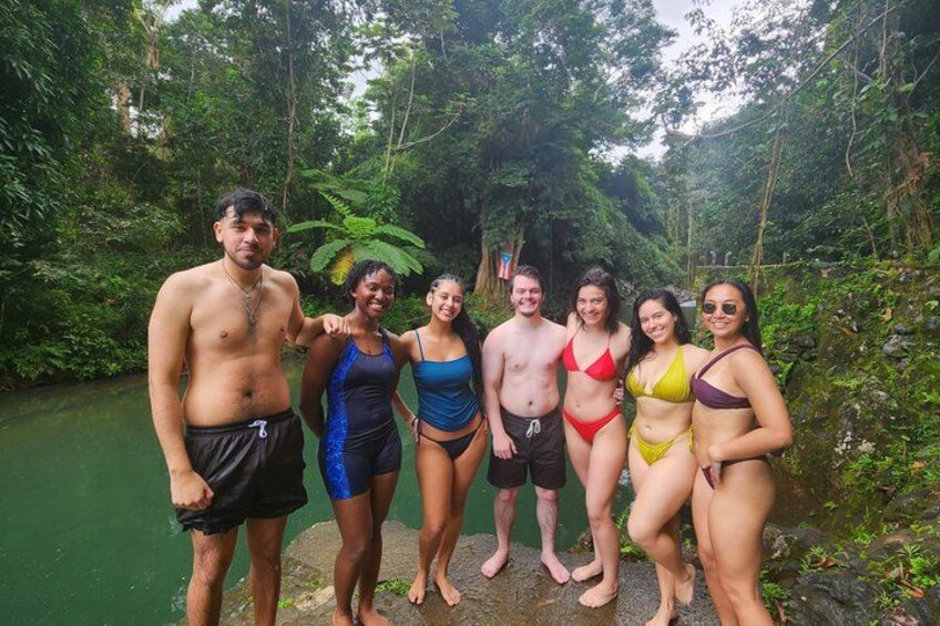A group of people standing by a river in a forested area. 2