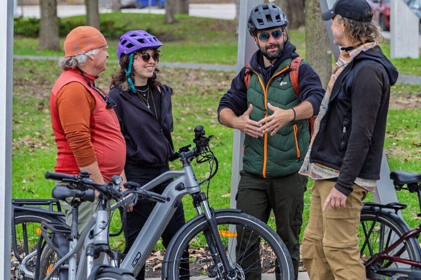Four people standing near bicycles in a park. 4