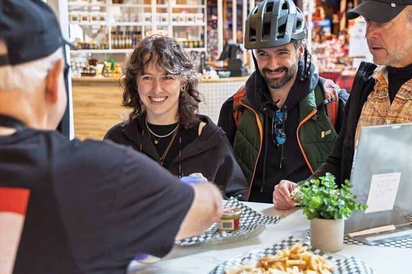Un grupo de personas sentadas a una mesa con comida, una computadora portátil y una planta. 3