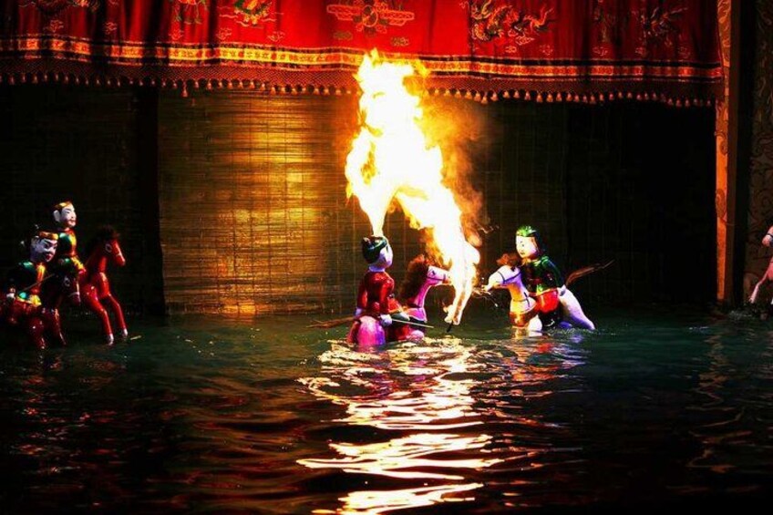 Performers in traditional costumes with a fire element in a water-based performance. 3