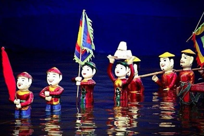 A group of people in traditional costumes, some holding flags, standing in water. 4
