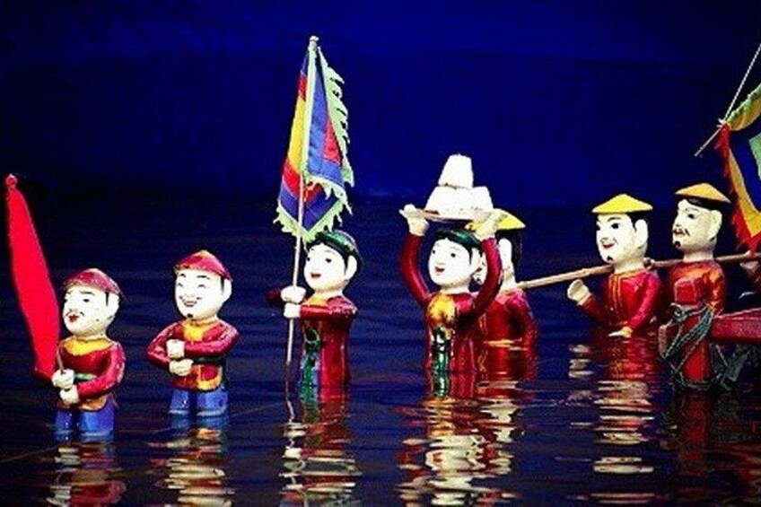 A group of people in traditional costumes, some holding flags, standing in water. 2