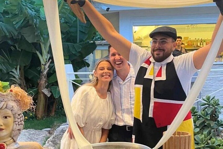 Une personne portant un gilet coloré et une femme en robe blanche posent avec un homme. 1