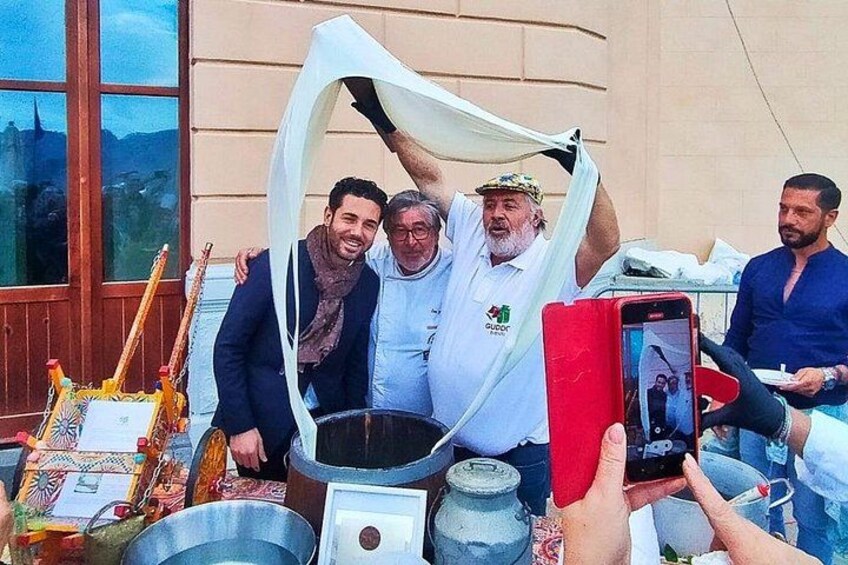 Un groupe de personnes réuni autour d’un espace de cuisson traditionnel, avec un grand pot et une sorte d’auvent en tissu. 2