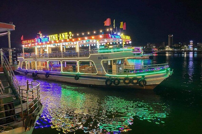 A brightly lit boat with multiple decks and colorful lights, docked at a harbor with reflections on the water. 2