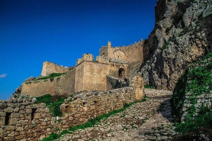 A historic stone castle perched on a rocky cliff, with a clear blue sky above. 3