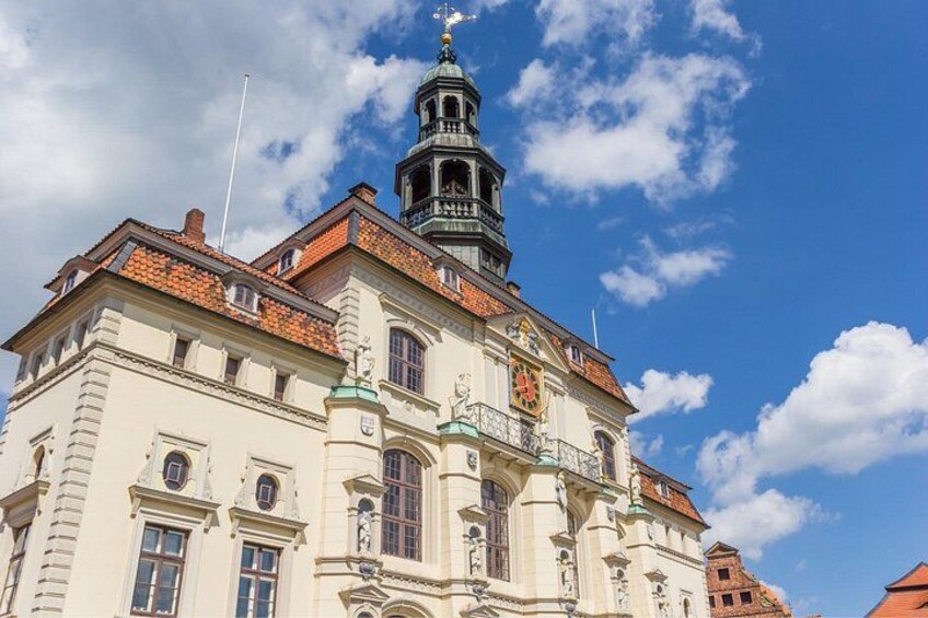A historic building with a clock tower, ornate windows, and a red-tiled roof. 5