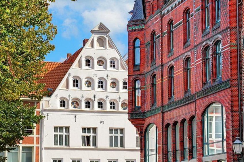 A white building with a triangular roof and a red brick building with arched windows. 3