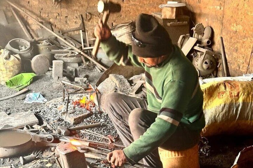 A person working with a fire in a cluttered workshop. 1
