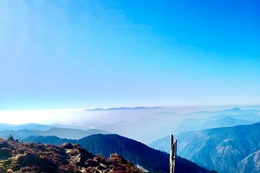 Un paysage de montagne avec un ciel dégagé et un poteau en bois au premier plan. 3