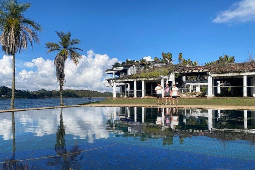 A swimming pool with palm trees and a building with a thatched roof. 3