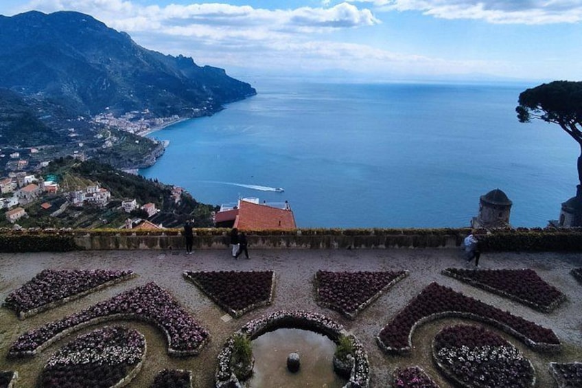 A coastal landscape with terraced gardens, a body of water, and a distant town. 3