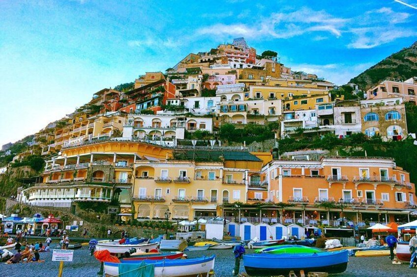 A hillside town with colorful buildings, boats on a beach, and a clear sky. 5