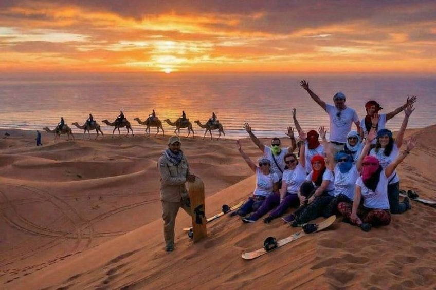 Un gruppo di persone a dorso di cammelli e cavalli in un deserto al tramonto. 2