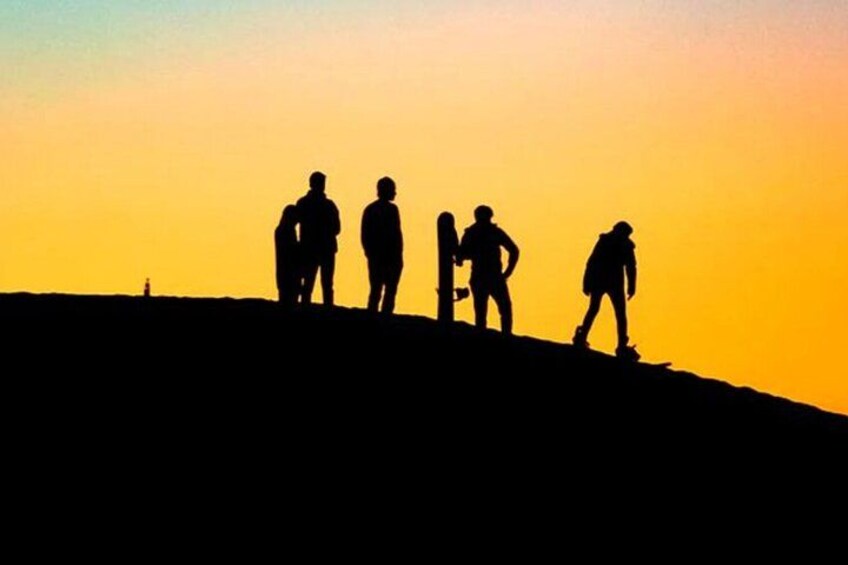 Een groep mensen staat op een heuvel tijdens de zonsondergang. 5