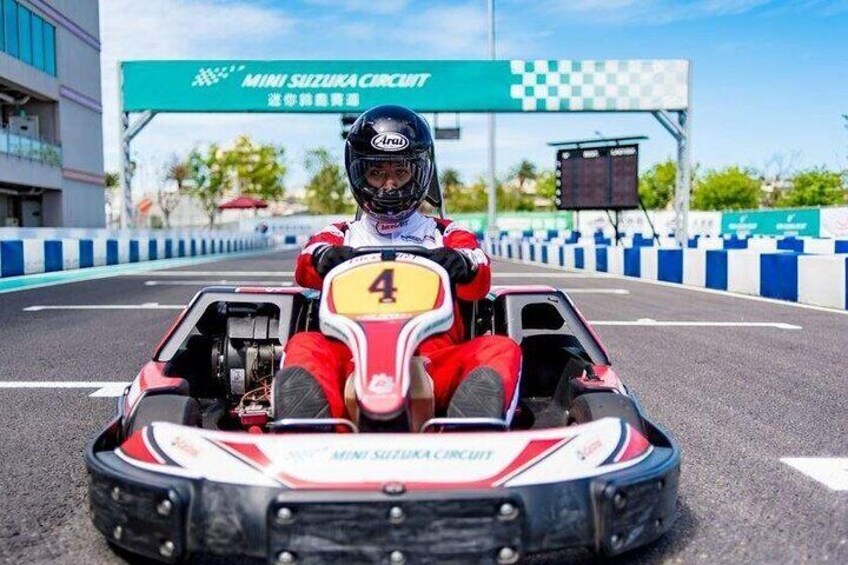 A go-kart on a race track with a sign reading "MINI SUZUKA CIRCUIT". 1