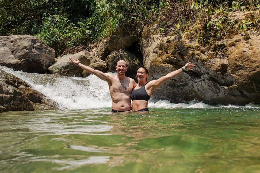 Zwei Personen in einer natürlichen Wasserlandschaft mit Wasserfall und felsigem Gelände. 1