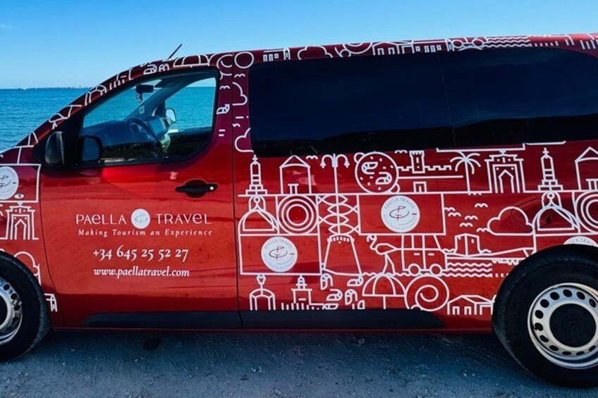 A red van with travel-related graphics and contact information. 2