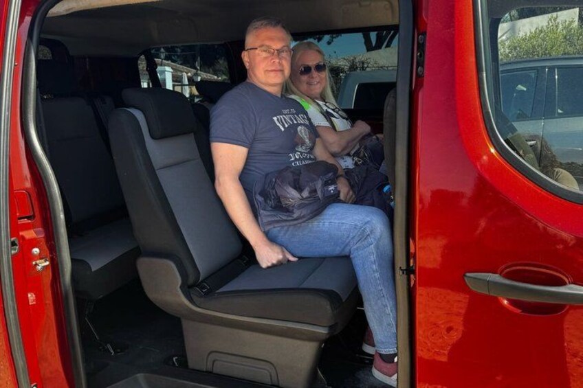 Un vehículo rojo con un hombre sentado en el asiento trasero sosteniendo una bolsa. 3