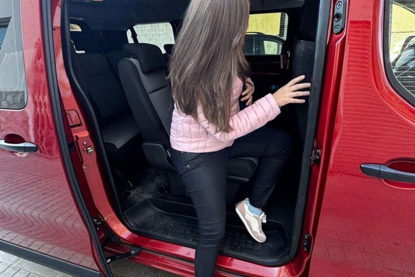 Una persona sentada en el asiento trasero de un vehículo rojo. 5