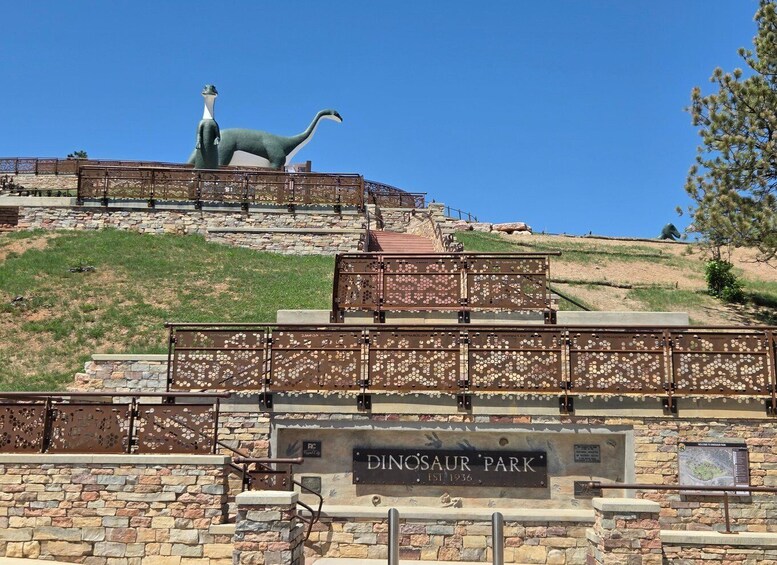 A dinosaur statue, a stone wall, and a sign reading 'DINOSAUR PARK.' 1
