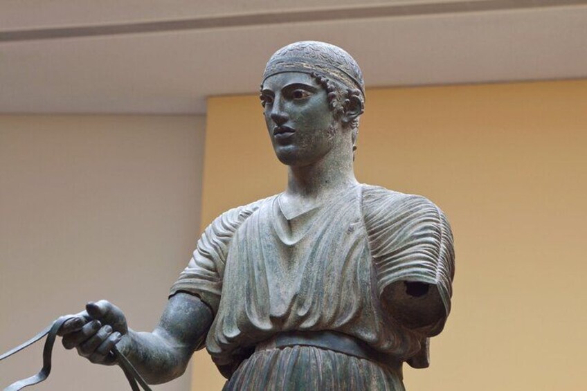 Eine bronzene Statue zeigt eine Figur, die eine Schriftrolle hält. 5