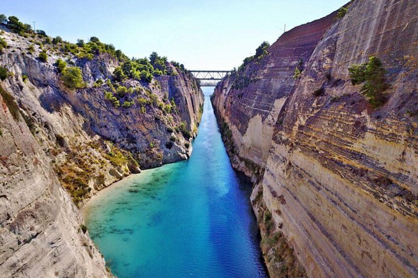 Ein Flusslauf durch eine Schlucht mit steilen Felswänden und einer Brücke. 3